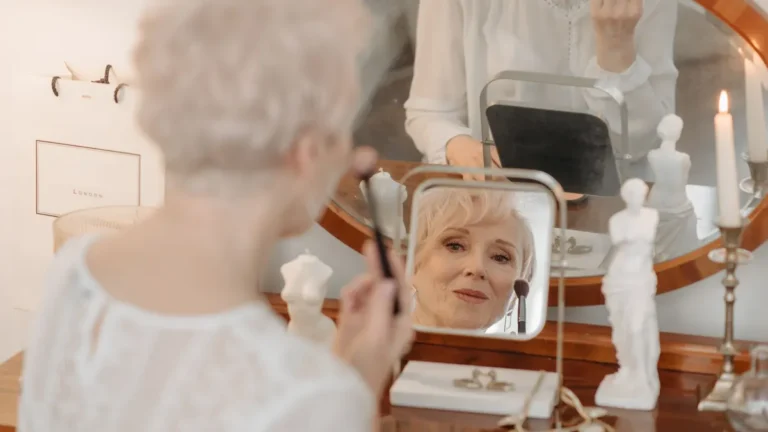 elegant senior woman applying lipstick mirror